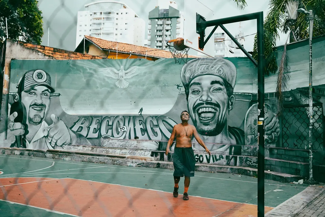 Mand på udendørs basketballbane med graffiti i baggrunden